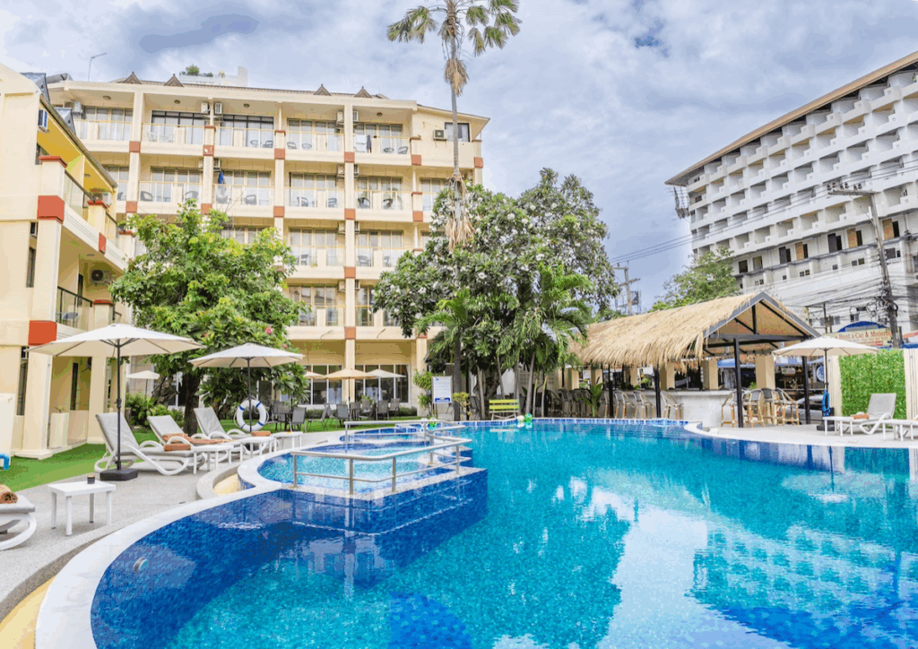 Swimming pool surrounded by lounge chairs and umbrellas at a hotel complex.